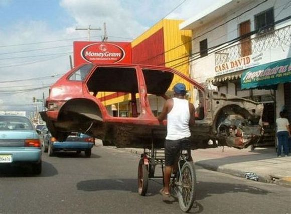 man on bicycle carying car chasis